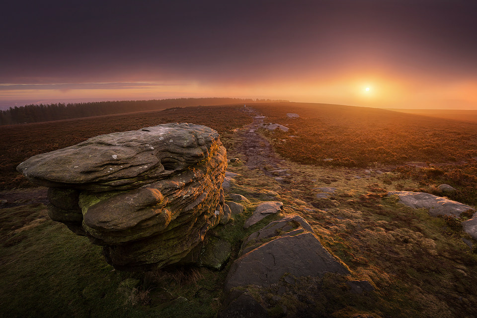 Ox stones Sunrise. With thick fog forecast for most of the Peak District, I decided to take a chance and catch the dawn at the Ox Stones. Just as the forecast had predicted though I arrived in thick murky fog. Not easily put off, I climbed on top of the stones and set up. As I waited the fog got thicker by the minute, it was starting to look like I wouldn't get a sunrise at all. Suddenly a patch of colour appeared on the horizon and light began to burn through the fog, creating a beautiful orange glow and illuminating the gritstone. A beautiful morning!