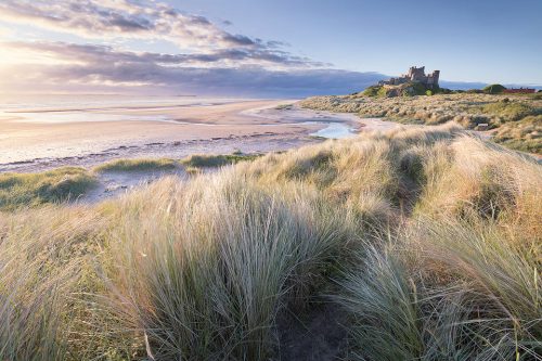 Beautiful summer sunrise at the iconic Bamburgh Castle on the North East Coast. After photographing the sunset and blue hour around Dunstanburgh we headed to Bamburgh for the sunrise. After an unpromising start the sun eventually managed to break through the low band of cloud and we got some stunning light.