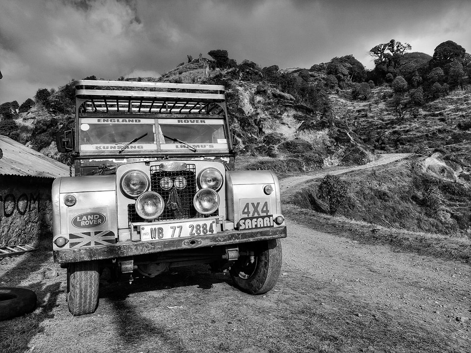 Black and white image of a converted British Landrover against a mountainous backdrop. Singalila National Park, India.